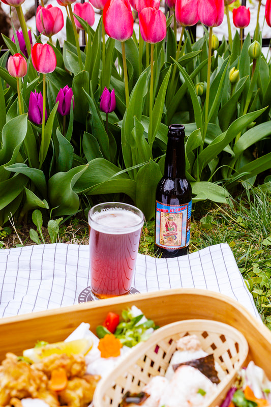 Italian craft beer shot in the garden with tulips in the background.