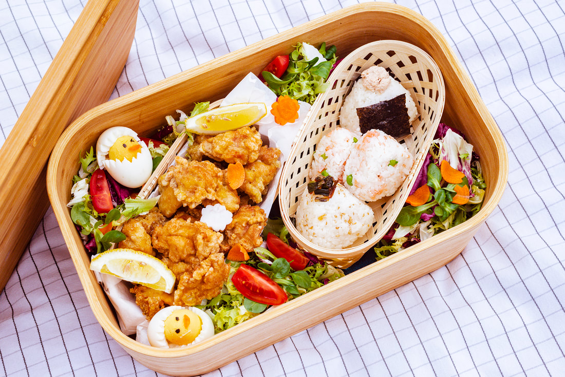 A large bento box filled with Karaage, Onigiri and some salad.