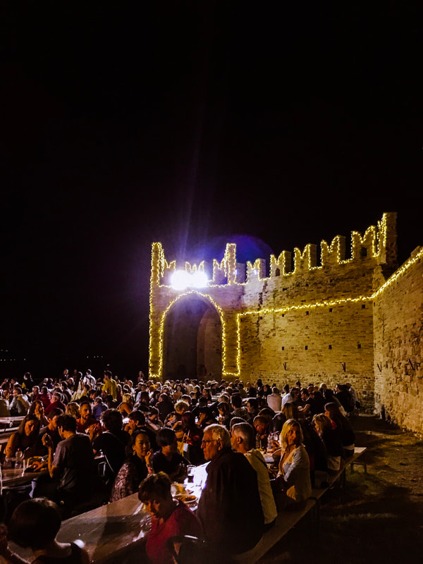 Outdoor theater of Campofilone packed with people during sagra di maccheroncini. Wall lighten by lights.