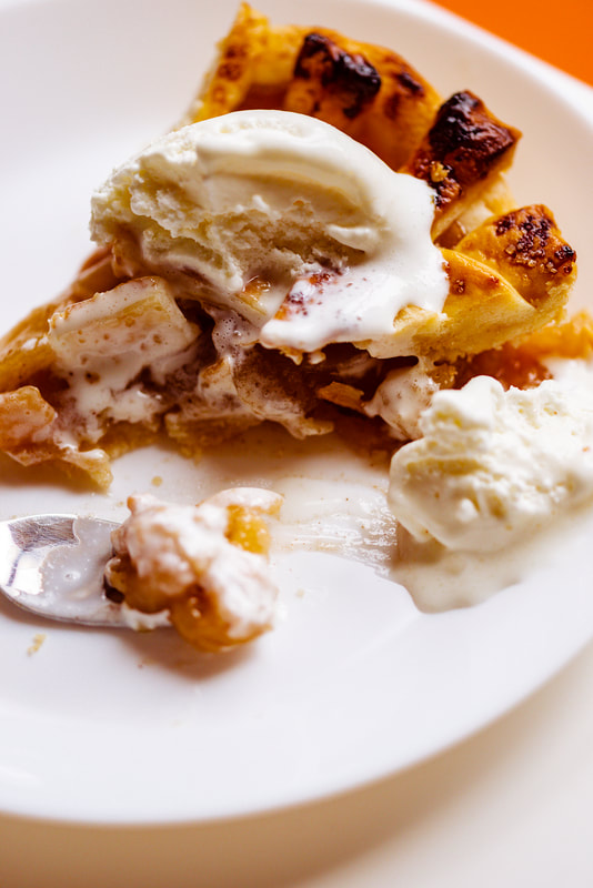 A half eaten apple pie with melting vanilla ice cream on top.