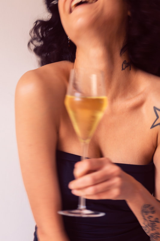 Blurry image of a tattooed female with a glass of sparkling wine